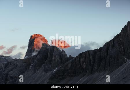 Soleil sur deux sommets et le brouillard sur les rochers. Tre Cime montagnes capturés à l'heure du coucher du soleil Banque D'Images