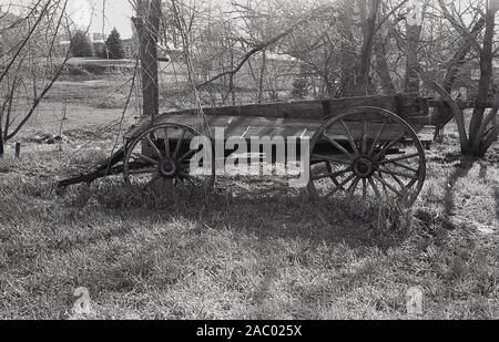 Années 1980, historique, ancien chariot à roues en bois abandonné dans le champ sur une ferme, Mid-West, USA. Banque D'Images