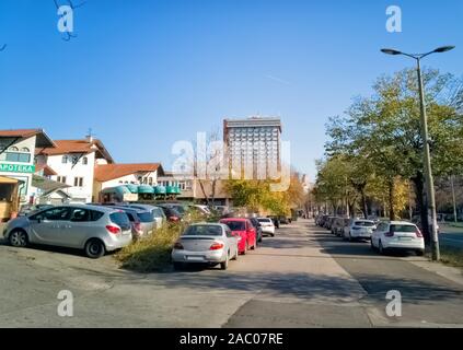 Ustanicka, Vozdovac, Belgrade, Serbie - 25 novembre 2019 : vue sur la rue, le trottoir et le stationnement avec des maisons et l'hôtel Serbie gratte-ciel dans la distance Banque D'Images