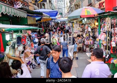Les acheteurs parcourent les produits d'un marché de rue animé de Hong Kong, à la recherche de trouvailles uniques et de produits locaux. Banque D'Images