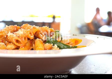 Pâtes Penne DANS LA SAUCE ARIABBATTA dans un bol blanc avec un fond bokeh Banque D'Images