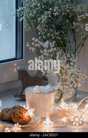 Gypsophila bouquet sur la fenêtre dans un vase de verre au crépuscule. Banque D'Images