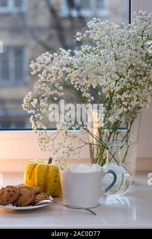 Gypsophila bouquet sur la fenêtre dans un vase de verre au crépuscule. Banque D'Images