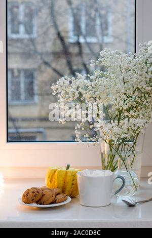 Gypsophila bouquet sur la fenêtre dans un vase de verre au crépuscule. Banque D'Images