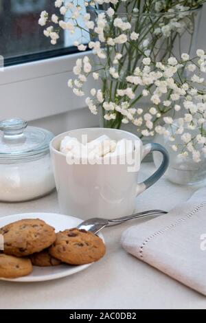 Gypsophila bouquet sur la fenêtre dans un vase de verre au crépuscule. Banque D'Images