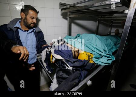 (NOTE DU RÉDACTEUR : Image représente la mort)Un agent de police palestinienne se dresse à côté du corps de 16 ans, Mohammed al-Astal, qui a été tué près de la frontière avec Israël, à une morgue de l'hôpital de Khan Younis. Les forces israéliennes ont tué un adolescent palestinien près de la frontière de Gaza, le ministère de la santé dans l'enclave à la gestion du Hamas dit. Mohameed al-Astal, 16 ans, est mort après avoir été touché à l'estomac à l'est de Khan Yunis dans le sud de Gaza, avec quatre autres Palestiniens blessés. Banque D'Images