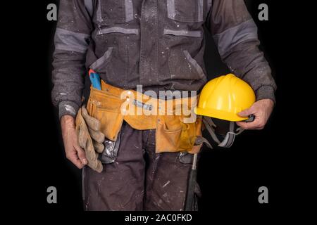 Painter holding un mur pinceau dans sa main. Accessoires pour les petites réparations à la maison. Fond sombre. Banque D'Images