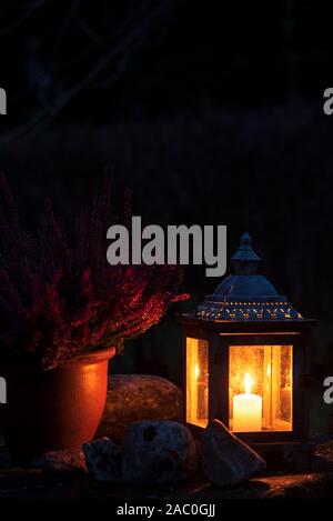 Ancienne lanterne à bougie brûlante et cache-pot en céramique, nuit noire dans le jardin Banque D'Images