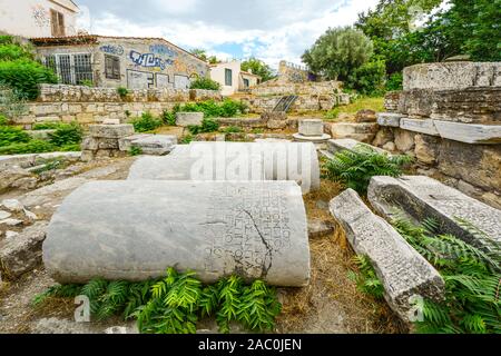 Colonnes antiques avec des inscriptions mises à côté d'un nouveau bâtiment couvert de graffitis à Athènes, Grèce. Banque D'Images