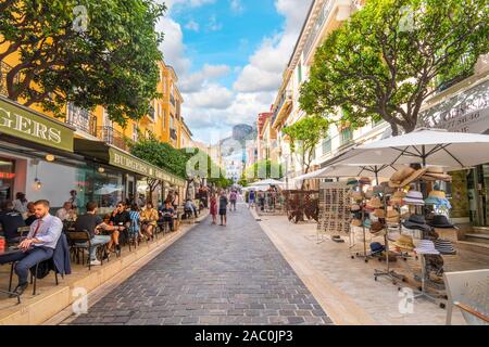 Les touristes locaux et profiter d'un Monégasque journée ensoleillée shopping et restaurants à Monte Carlo, Monaco, avec les montagnes au loin. Banque D'Images