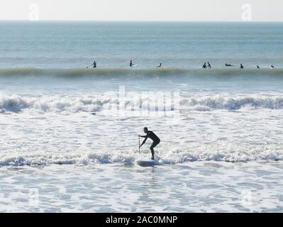 Surf d'hiver à Selsey beach en février 2019 avec un bassin pour surfer dans les vagues debout sur sa planche de surf dans les eaux seafoam Banque D'Images