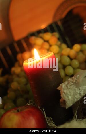 La chaleur de la maison d'automne encore la vie. Bougie brune lumière douce sur table avec raisins verts frais et pomme rouge avec guitare Banque D'Images