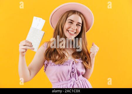 Image d'une jeune fille isolée joyeux sur jaune wall background wearing hat munis de billets et passeports faire geste gagnant. Banque D'Images