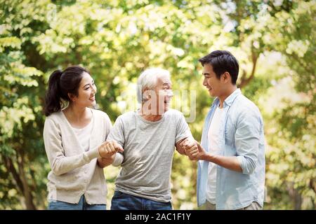 Young Asian man et woman helping senior man se lever et marcher Banque D'Images