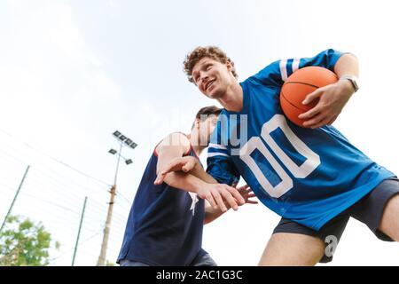 Confiant deux sportifs fit jouer au basket-ball sur un terrain de jeu Banque D'Images