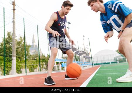 Confiant deux sportifs fit jouer au basket-ball sur un terrain de jeu Banque D'Images