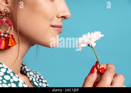 Close up side view portrait Portrait d'une charmante jeune femme portant chemise et des boucles d'isolés sur fond bleu, chamomil holding Banque D'Images