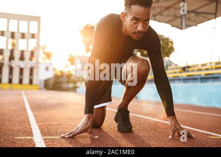 Image de young african american man getting prêt à fonctionner sur les stades sportifs en plein air Banque D'Images