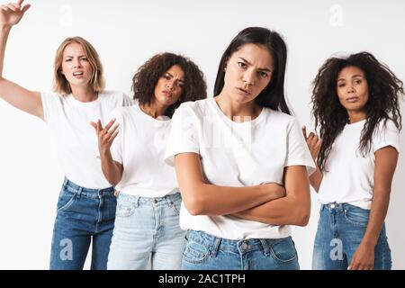 Photo d'une des jeunes femmes grave déplu friends posing multiraciale isolated over white wall background. Banque D'Images