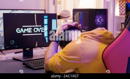 Au-dessus de l'épaule avec des professionnel homme jouant les jeux vidéos dans une salle avec des néons colorés. Banque D'Images