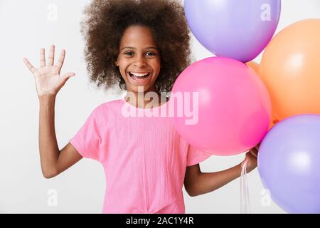 Peu gaie african girl wearing pink blouse isolés sur fond blanc, ayant à la main, agitant des ballons d'air Banque D'Images