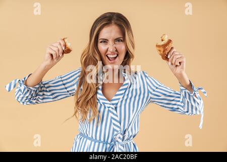 Portrait d'une jolie jeune femme en colère avec de longs cheveux blonds portant des vêtements isolés sur fond beige, larmoiement crois Banque D'Images