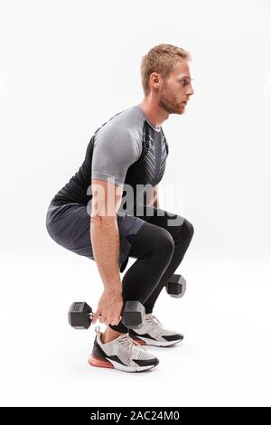 Certain young sportsman musculaires isolés sur fond blanc, de soulever des poids lourds, les squats d'haltères longues Banque D'Images