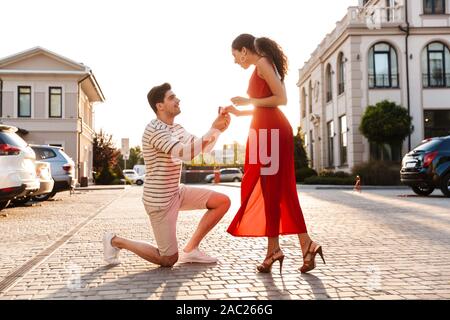 Image homme poils faire demande en mariage à sa petite amie avec anneau en boite cadeau en marchant au city street Banque D'Images