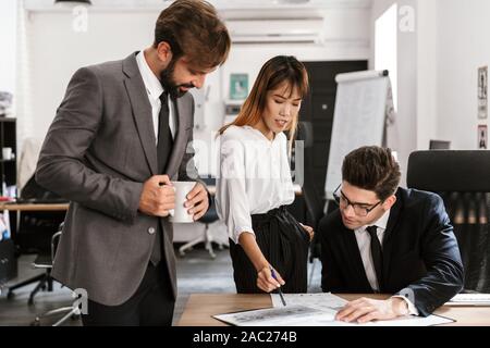 Photo de l'accent collègues discuter de projet et de boire du café tout en travaillant dans des bureaux à aire ouverte Banque D'Images