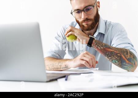 Image jeune homme portant des lunettes et des écouteurs holding tennis ballon en working in office Banque D'Images
