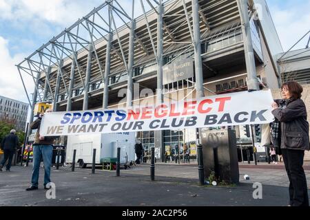 Newcastle, Angleterre, Royaume-Uni. 30 novembre, 2019. Les membres du Groupe Magpie, un groupe opposé au propriétaire du club, Mike Ashley, (propriétaire de Sports Direct), tenir une négligence 'Sports' bannière à l'extérieur St James' Park à l'avance du Newcastle accueil match contre Manchester City. Credit : Alan Dawson /Alamy Live News Banque D'Images