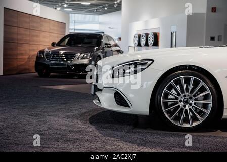 Attension à l'avant du véhicule blanc. Deux voitures garées dans auto show avec roues sur le mur à l'arrière-plan Banque D'Images