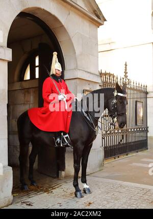 Household Cavalry dans leurs longs manteaux traditionnels uniforme rouge à Whitehall, Londres, UK Banque D'Images