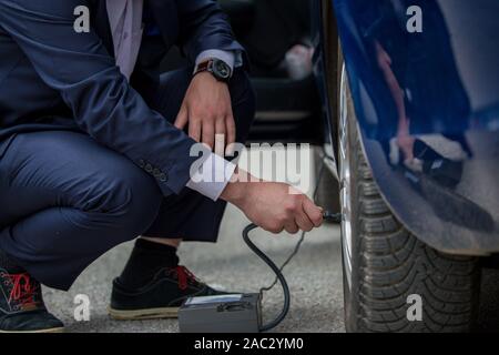 Changer le caoutchouc fissuré sur la voiture, les pneus en caoutchouc soufflé avec compresseur, premiers secours sur la route Banque D'Images