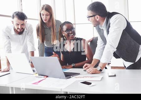 Se sentir satisfait. Quatre employés multiraciale ont travailler au bureau à l'aide de l'ordinateur portable sur la table Banque D'Images