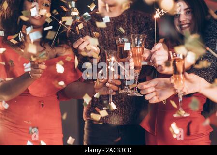 Avoir la bonne humeur et de bon temps. Amis multiraciale fêter le nouvel an et la tenue des feux de Bengale et lunettes avec verre Banque D'Images