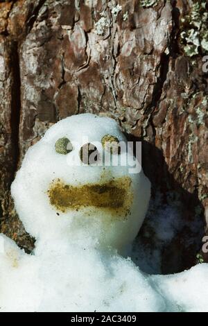 Le Snowman figurine sur un tronc d'arbre. Les personnages de conte de Noël l'hiver Banque D'Images