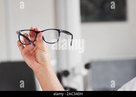 Axé photo. Main femme détient les lunettes bleu dans le cabinet du médecin Banque D'Images