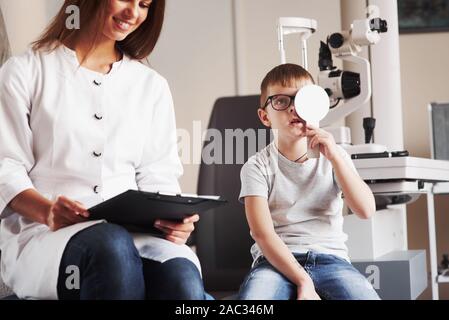 Amour femme ressemble à son emploi. Femme avec des tests d'acuité visuelle les documents de petit garçon Banque D'Images