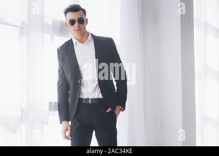 Portrait de jeune homme élégant à porter d'affaires classique debout dans la chambre blanche Banque D'Images