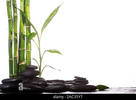 Grean sur des feuilles de bambou zen stones noir pyramide sur fond blanc Banque D'Images