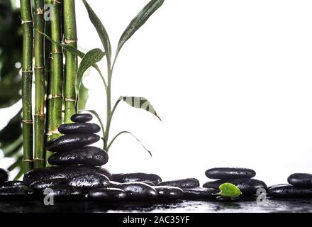 Grean sur des feuilles de bambou zen stones noir pyramide sur fond blanc Banque D'Images