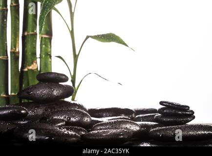 Grean sur des feuilles de bambou zen stones noir pyramide sur fond blanc Banque D'Images