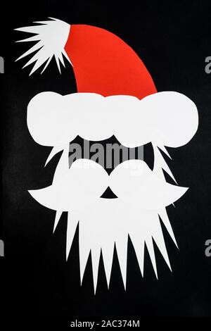 Composition abstraite de la tête du Père Noël avec les faits de papier rouge et blanc nd mis sur fond gris et noir foncé with copy space Banque D'Images