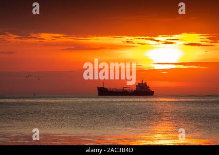 Scène silhouette de navire et aux Mouettes volantes avec orange ciel nuageux au lever du soleil. Banque D'Images