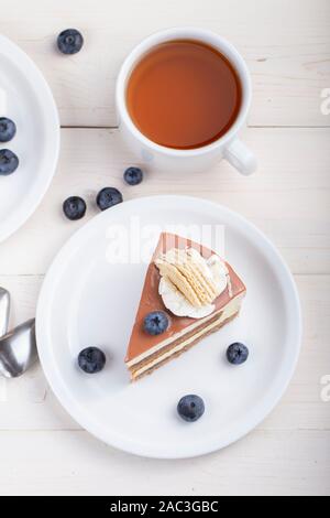 Dans une tasse de thé et une tranche de gâteau au chocolat ou de café dans une assiette sur la table. gourmandise pour la maison de vacances. Vue de dessus Banque D'Images