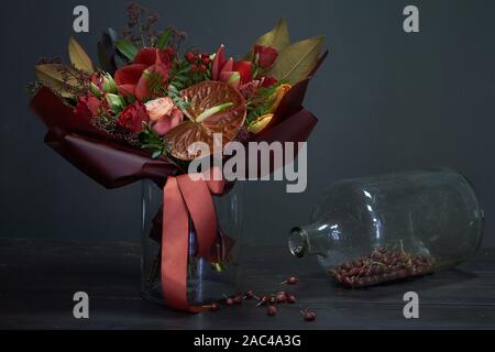 Bouquet d'automne chic en rouge les couleurs dans le style vintage dans un vase en verre et un énorme pot d'églantier à sec sur un fond sombre, selective focus Banque D'Images