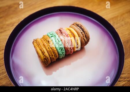 Vue rapprochée de délicieux macarons français authentique multicolores fabriqués à partir de produits bio de luxe sur la plaque violette prêt à être manger Banque D'Images