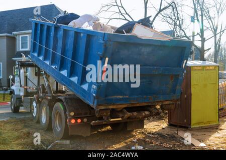 L'enlèvement des débris de démolition de bâtiments avec des déchets de construction et de gravats de béton rock on portable bio toilettes cabines sur le site de construction Banque D'Images