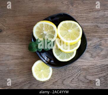 La menthe fraîche herb et citrons dans une plaque noire sur fond de bois gris rustique Banque D'Images